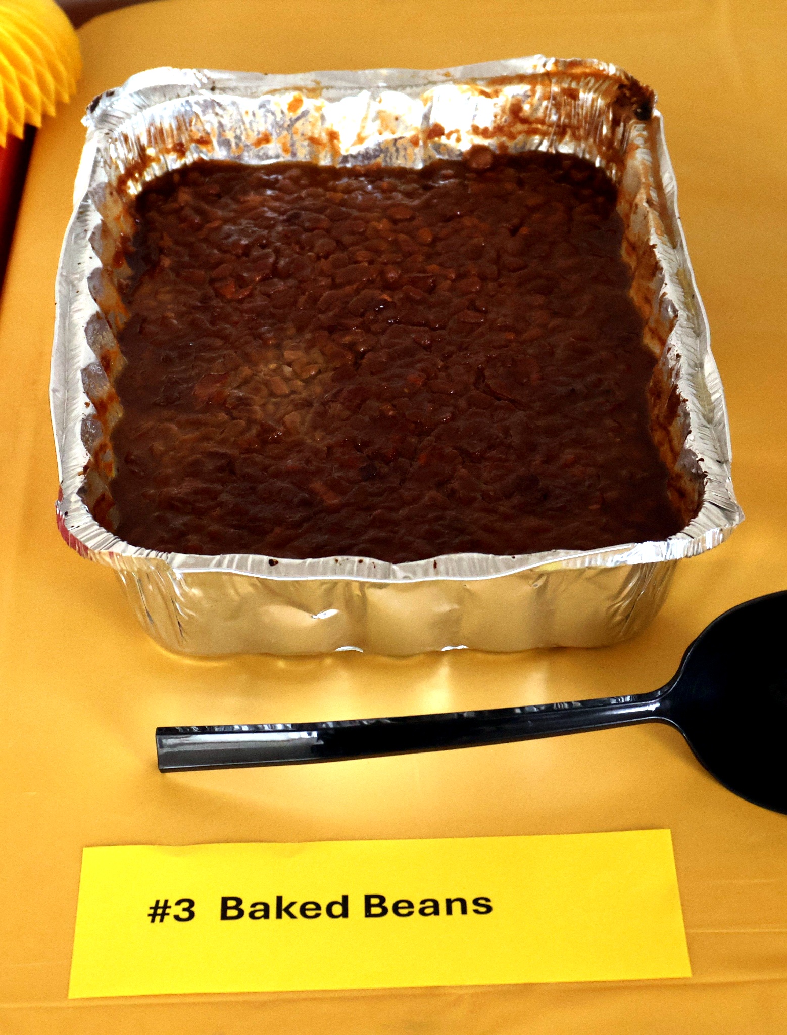 Image of baked beans on a yellow tablecloth